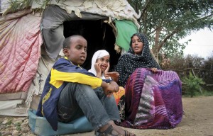 Ubah Mohammed Abdule, right, the mother of the 15 year old Somali boy who stowed away on a flight from California to Hawaii, is interviewed at a refugee camp in Ethiopia. She is sitting in front of a tent and two children are next to her.